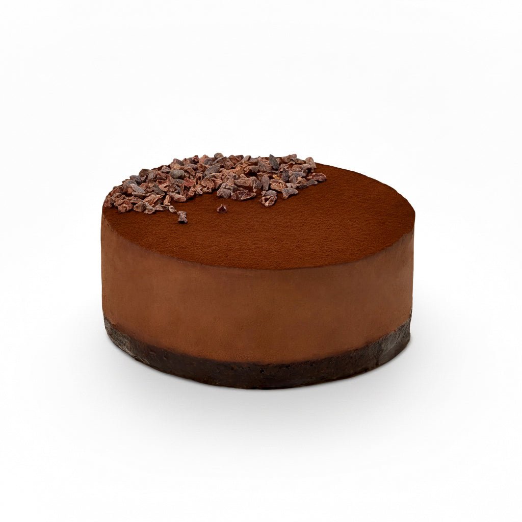 Round rich Chocolate cake with cocoa powder and cacao nibs topping on white background