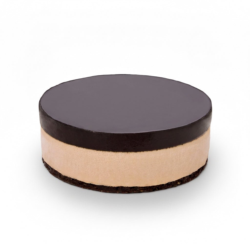Round layered raw vegan cake with dark chocolate top and creamy middle layer called Lucuma